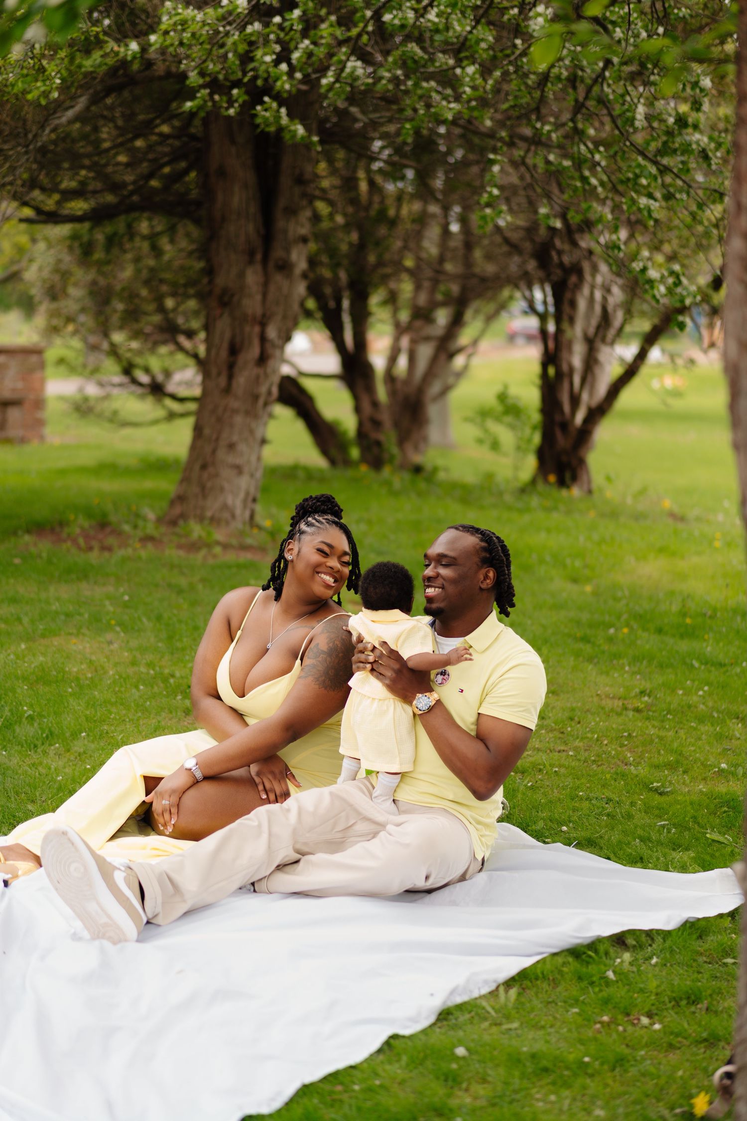 Couple sharing a joyful moment while relaxing on a blanket during an outdoor picnic under blooming trees.