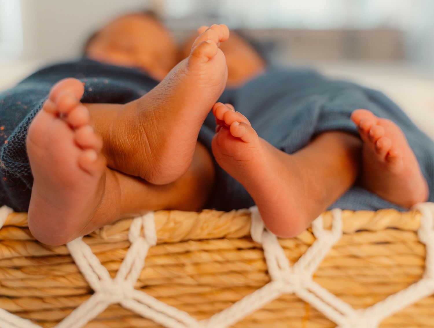Close up view of tiny baby feet laying on a woven blanket with criss-cross patterns.