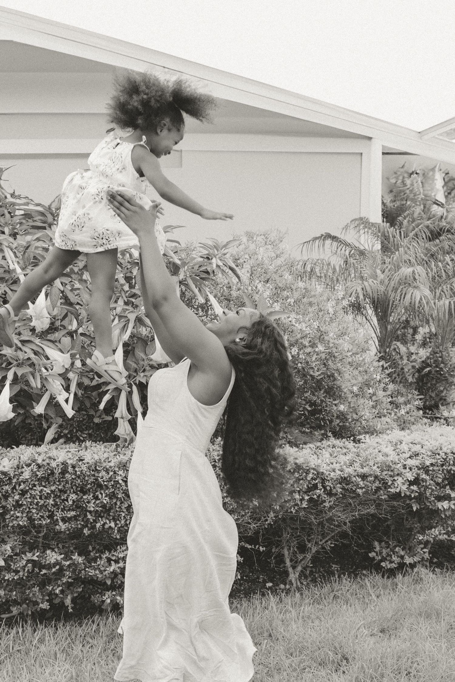 Heartwarming moment of parent lifting child high into the air during outdoor playtime.