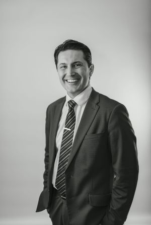 Black and white professional portrait showing a confident expression in business attire.