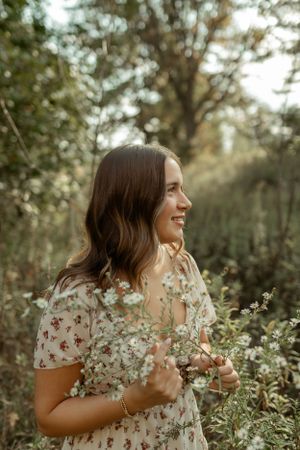 Natural outdoor portrait in a floral dress among wildflowers at golden hour.