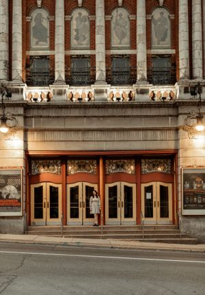 Historic theatre entrance with ornate stonework and vintage doors illuminated at twilight.
