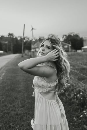 Black and white portrait in a rural setting with windswept hair and dramatic pose.