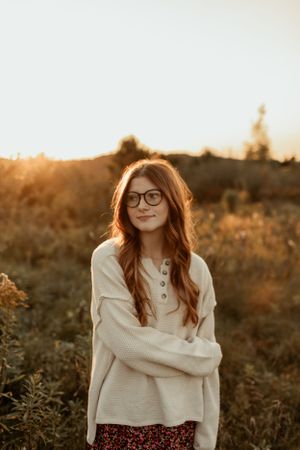 Golden hour portrait in cream sweater against sunset lit field.