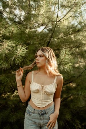 Summer portrait against pine trees with sunlight filtering through branches.