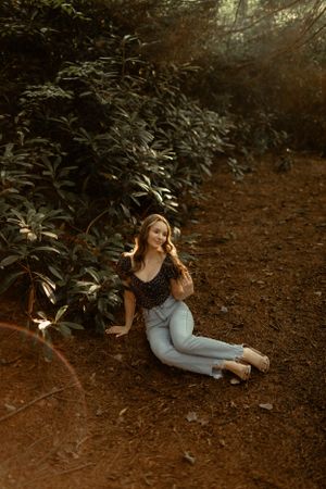 Nature-inspired portrait on dirt path surrounded by lush greenery at golden hour.