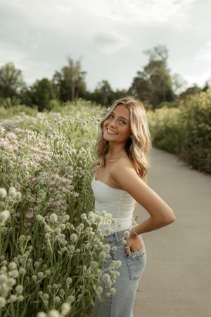 Portrait photography in a field of white wildflowers along a paved path during golden hour.