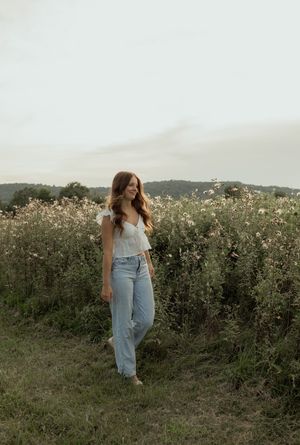 A person in denim overalls walks through a wildflower field at sunset creating a dreamy summer scene.