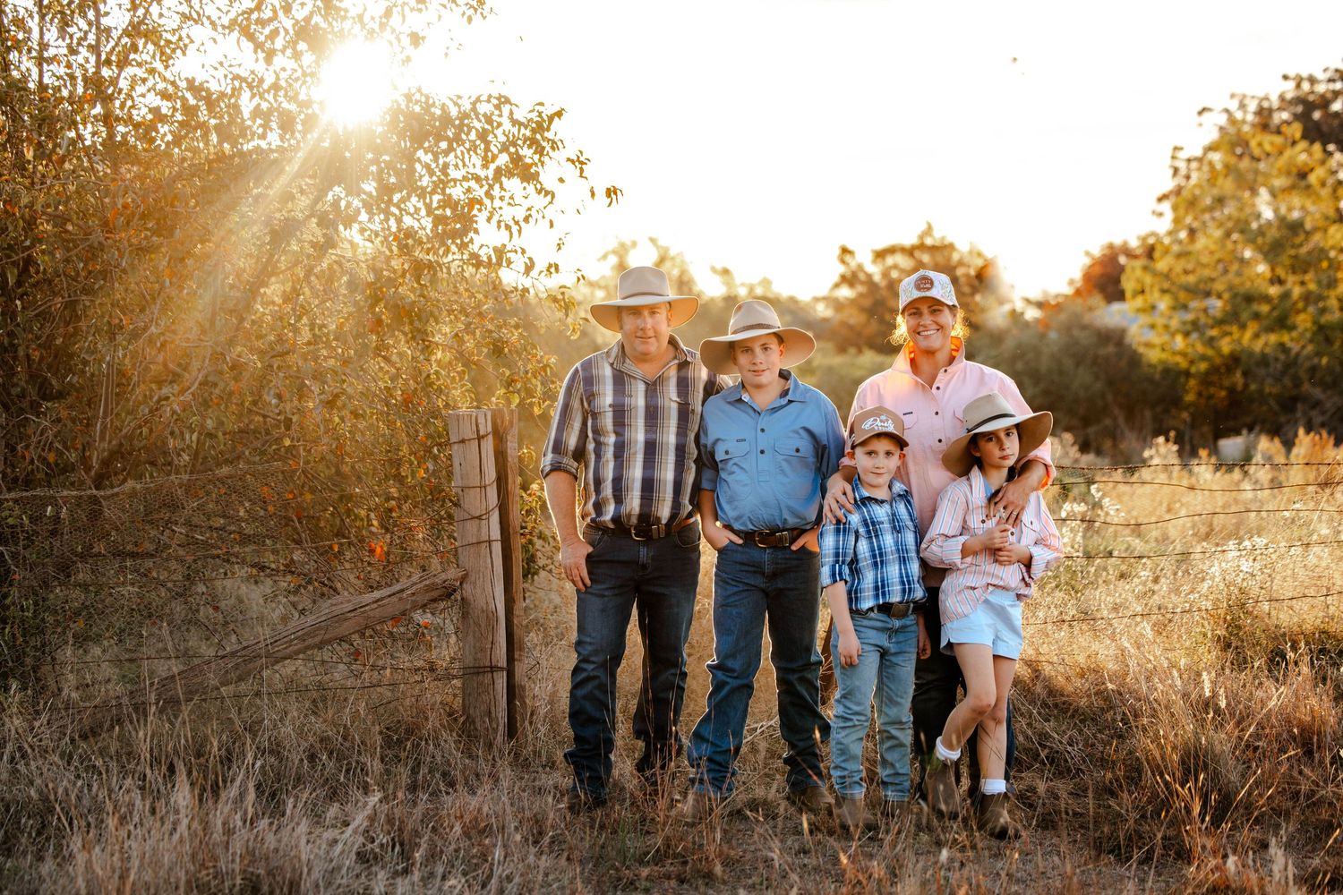 Romantic couple in white outfits embracing on a dirt road at sunset.