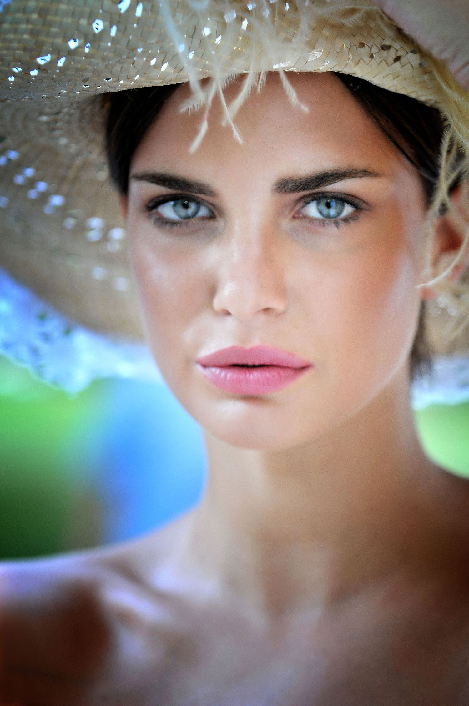 Summer portrait wearing straw hat with soft bokeh background.