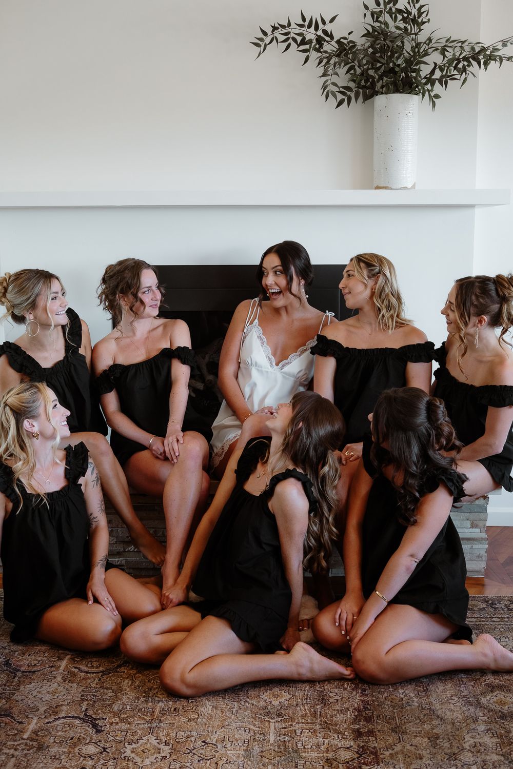 A boudoir photo session shows a group of women in black outfits posing together in an artistic floor pose.