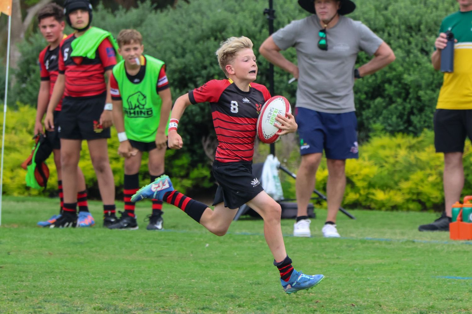 San Diego sports photography of a young rugby player running with the ball during a youth rugby match on a grass field.