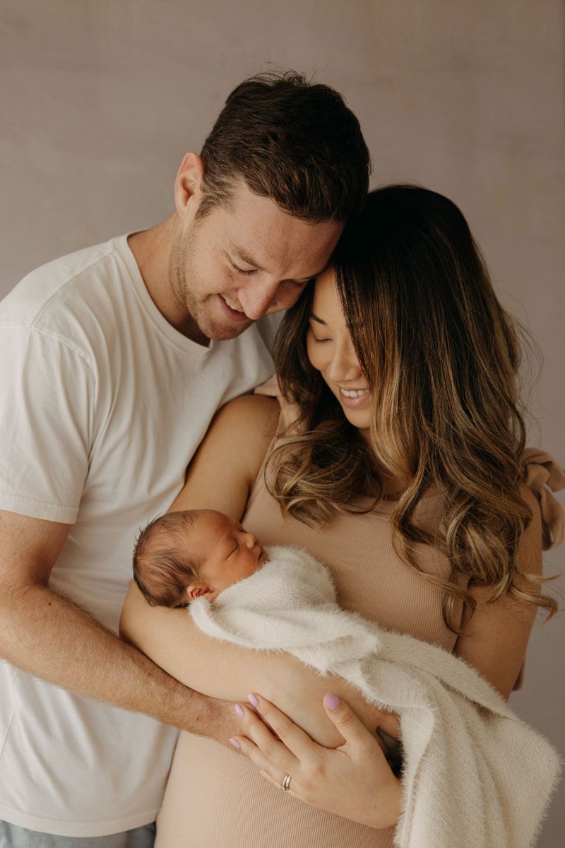 Intimate maternity photos showing tender moments between parents and newborn baby.
