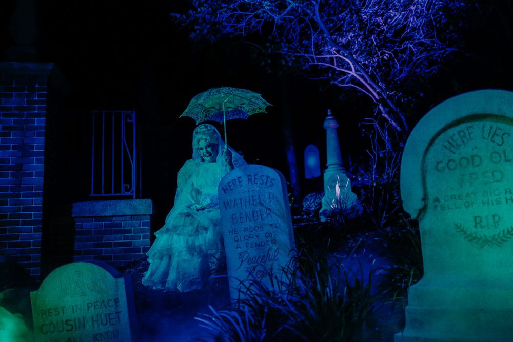 Spooky blue-lit ghost decoration in a haunted graveyard scene with tombstones.