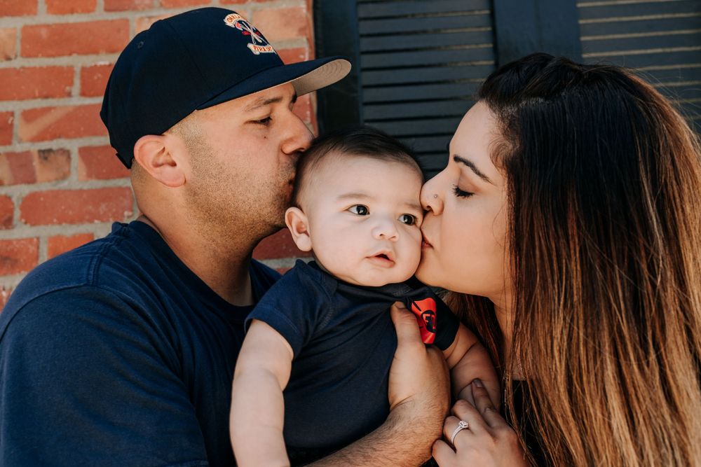 Family sharing sweet moment with baby against brick wall background.
