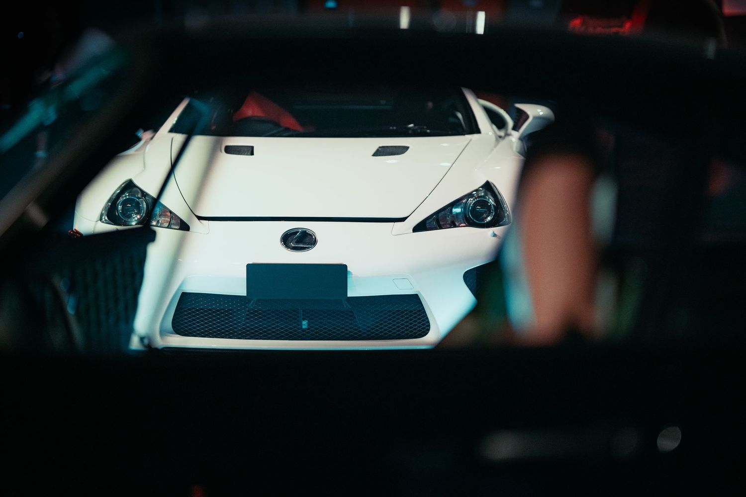 Close-up view of a white sports car front end in low light conditions.