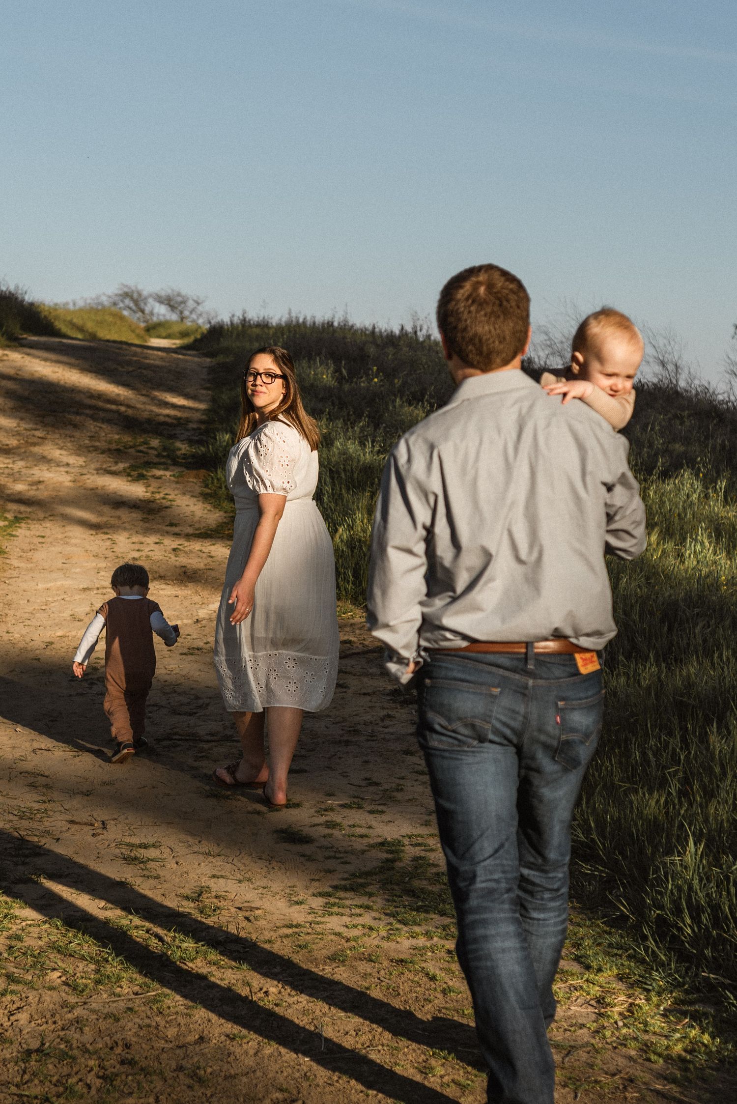 Family walking along a scenic dirt trail during sunset in an open space near Walnut Creek, CA.