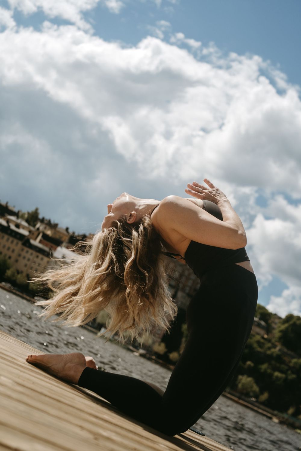 a woman bending over in a yoga pose with Stockholm buildings in background during brand photoshoot in Stockholm