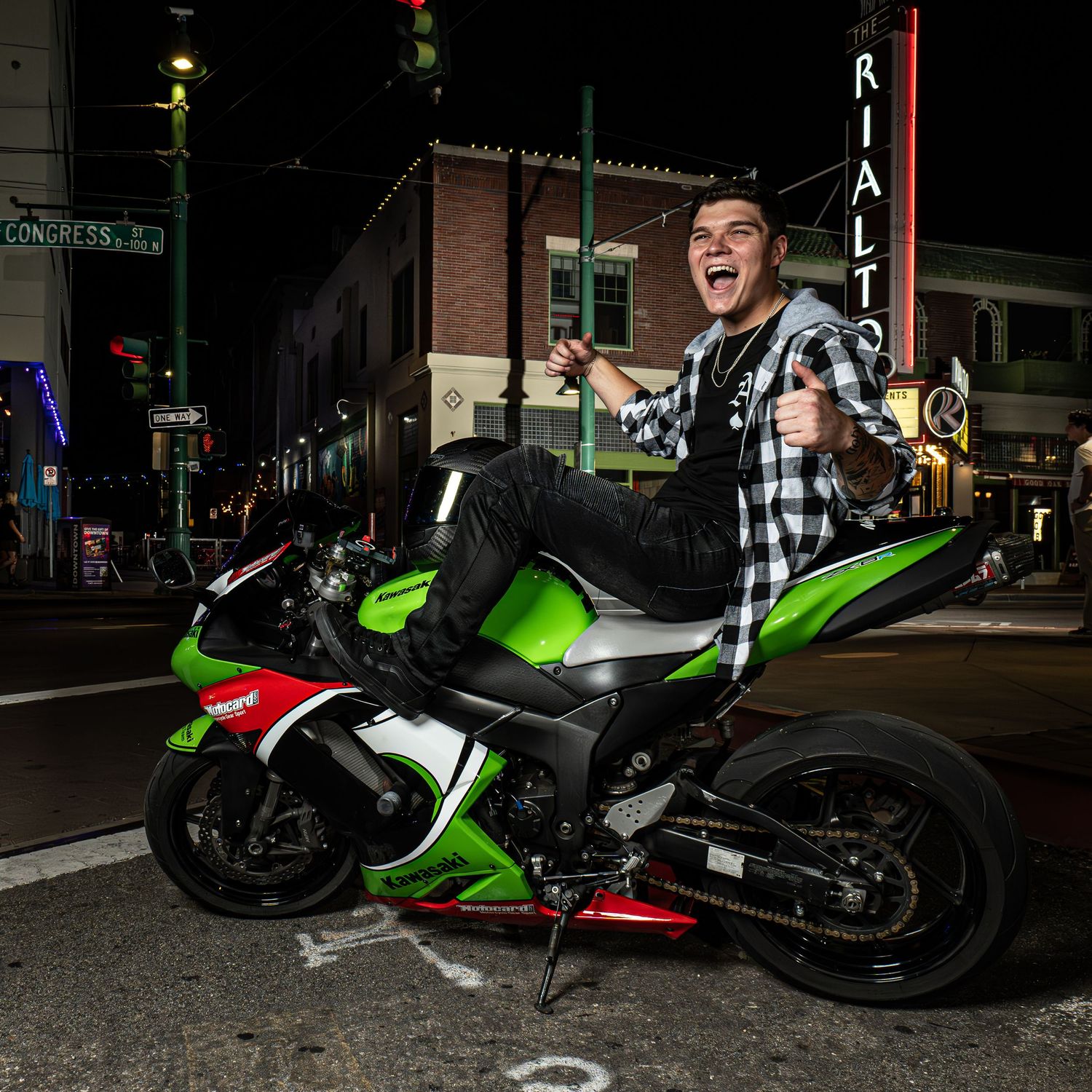 Excited person on green sport motorcycle at night under city lights.