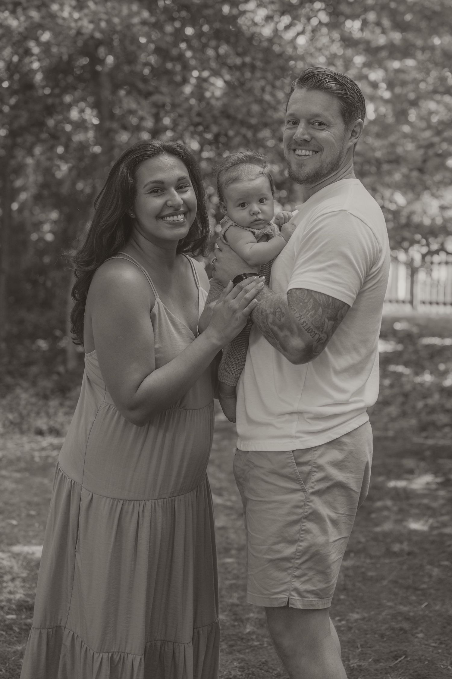A happy family of three shares a joyful moment together outdoors in a black and white photograph by Samantha Campbell imagery