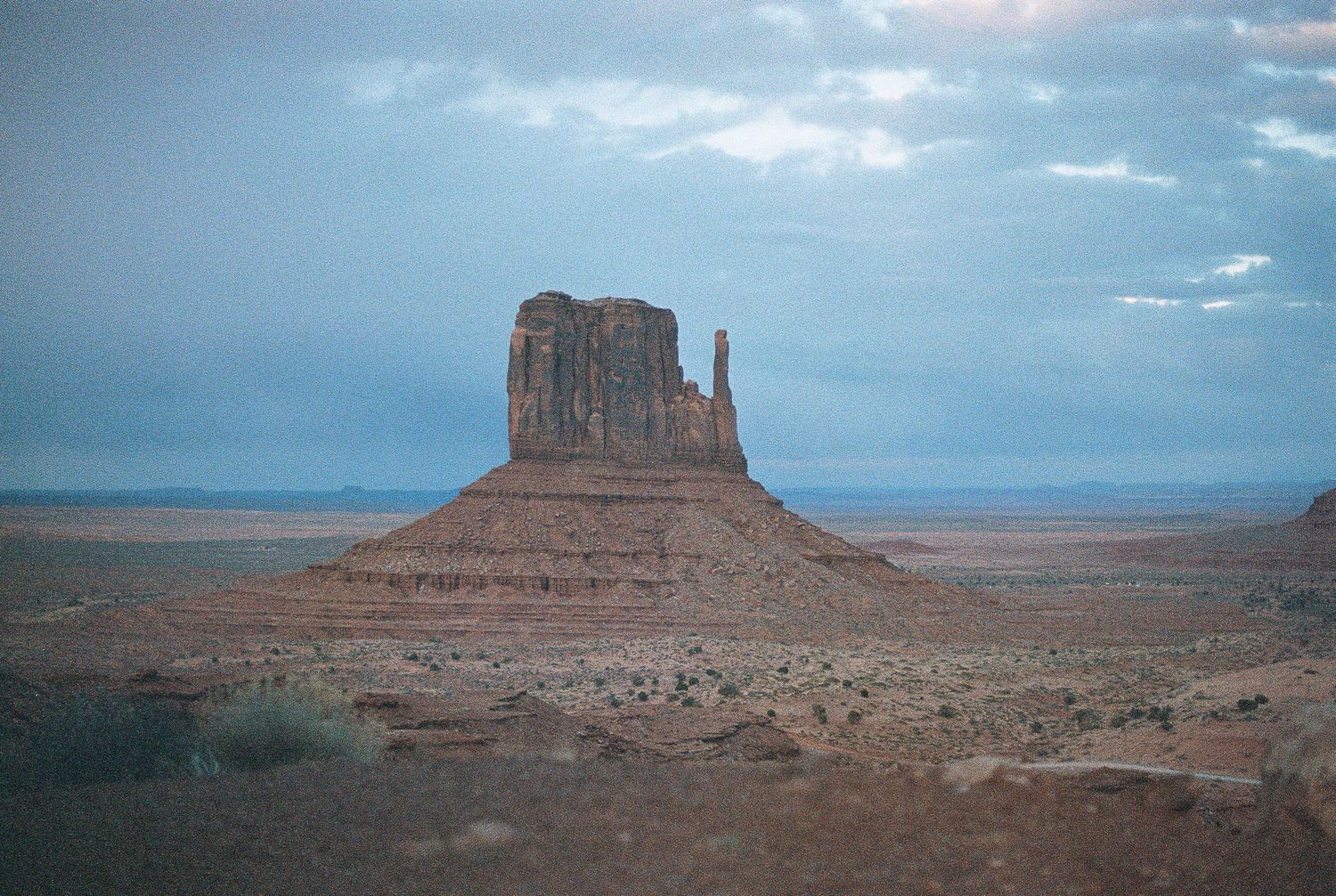Dramatic desert landscape with iconic Monument Valley buttes under blue skies.
