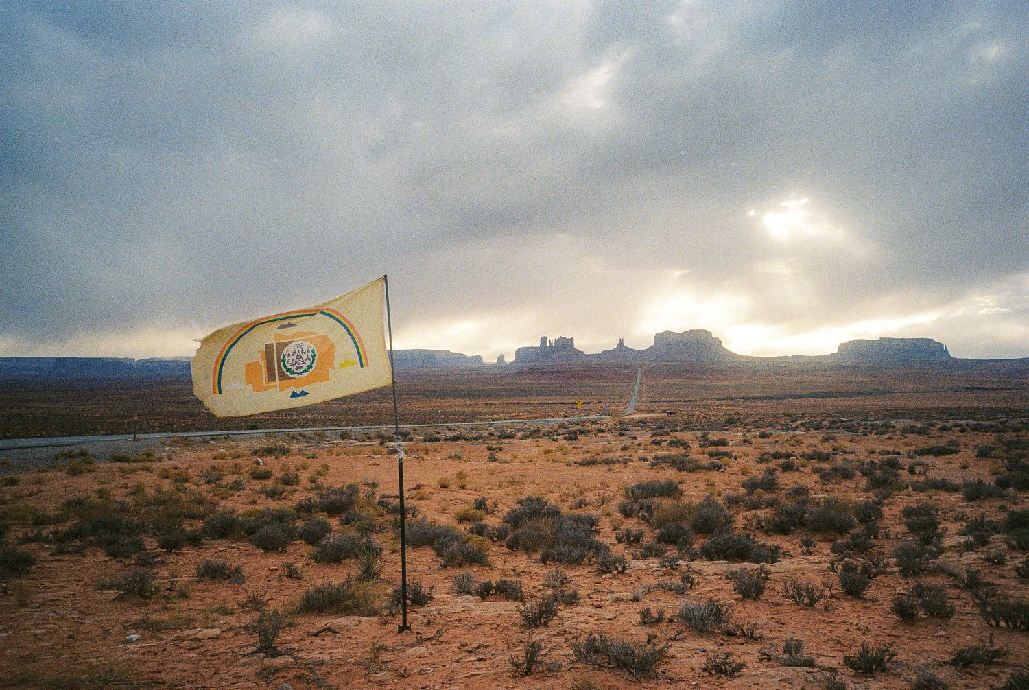 Panoramic desert landscape with dramatic cloudy sky and distant rock formations.