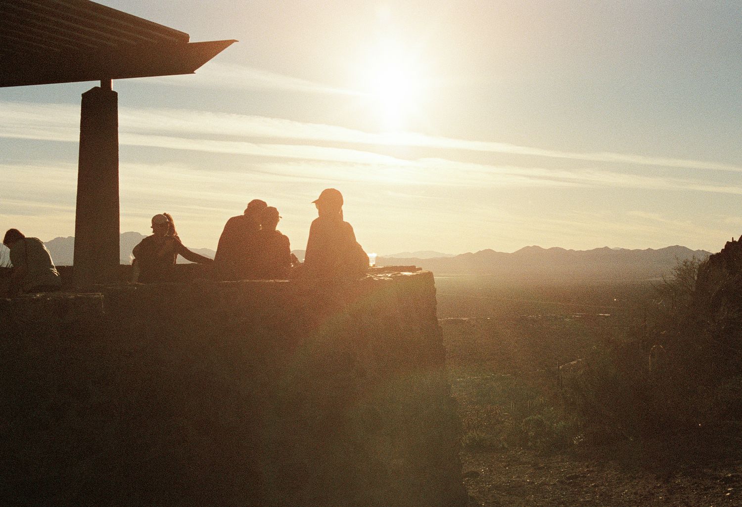 Silhouettes of rock formations against a dramatic sunset sky in the desert.