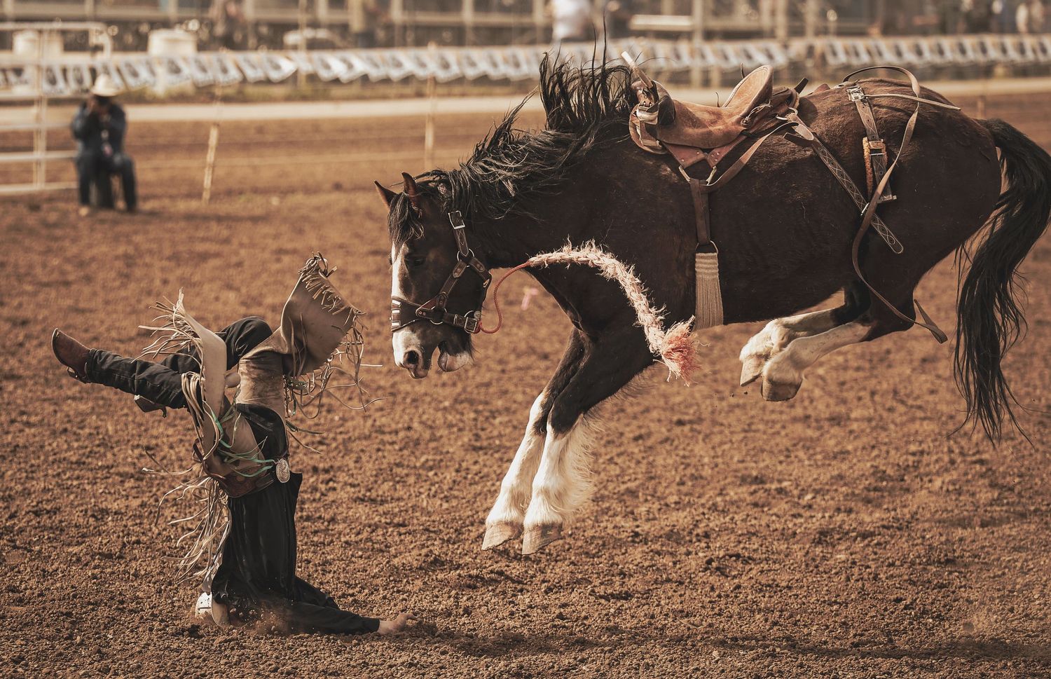A dramatic scene of a bucking horse throwing its rider during a rodeo competition.