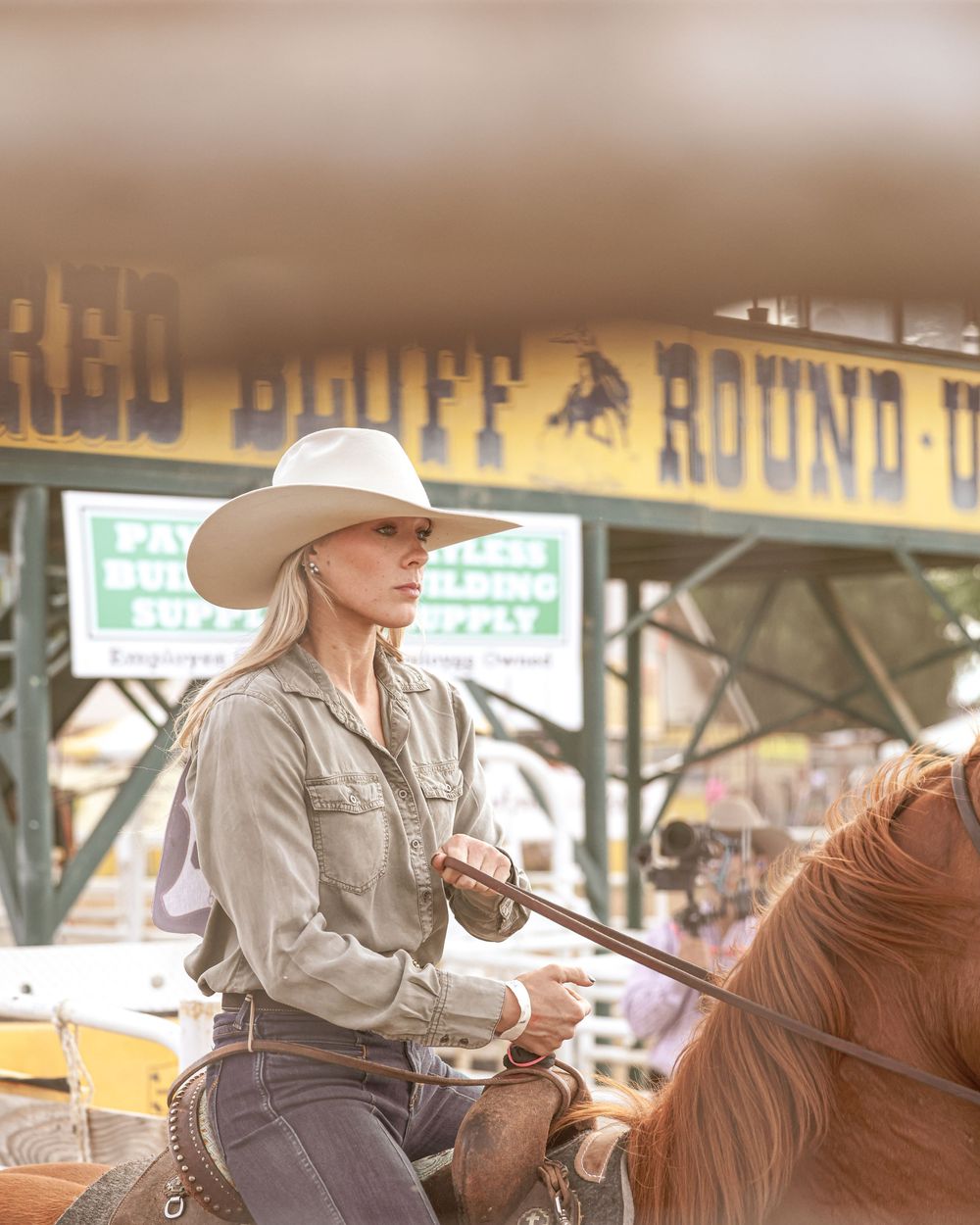 A blonde woman in a white cowboy hat rides a horse at the Red Bluff Round-Up rodeo event.