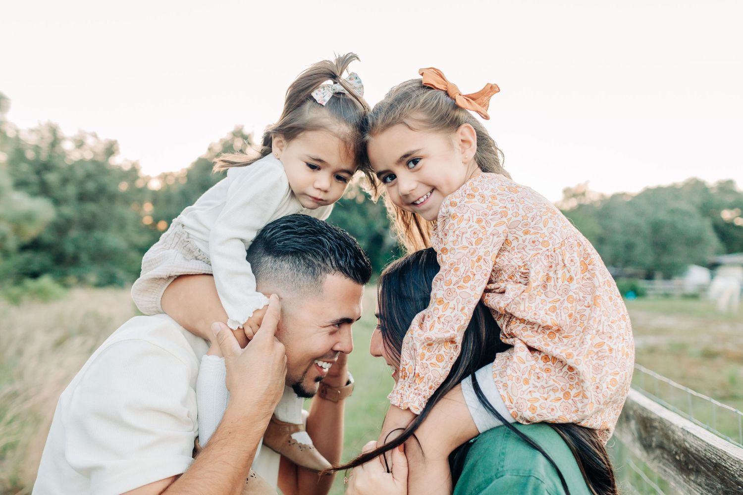 Fun family photo session with 2 little girls laughing on mom and dad's shoulders during a family photo session in Orlando