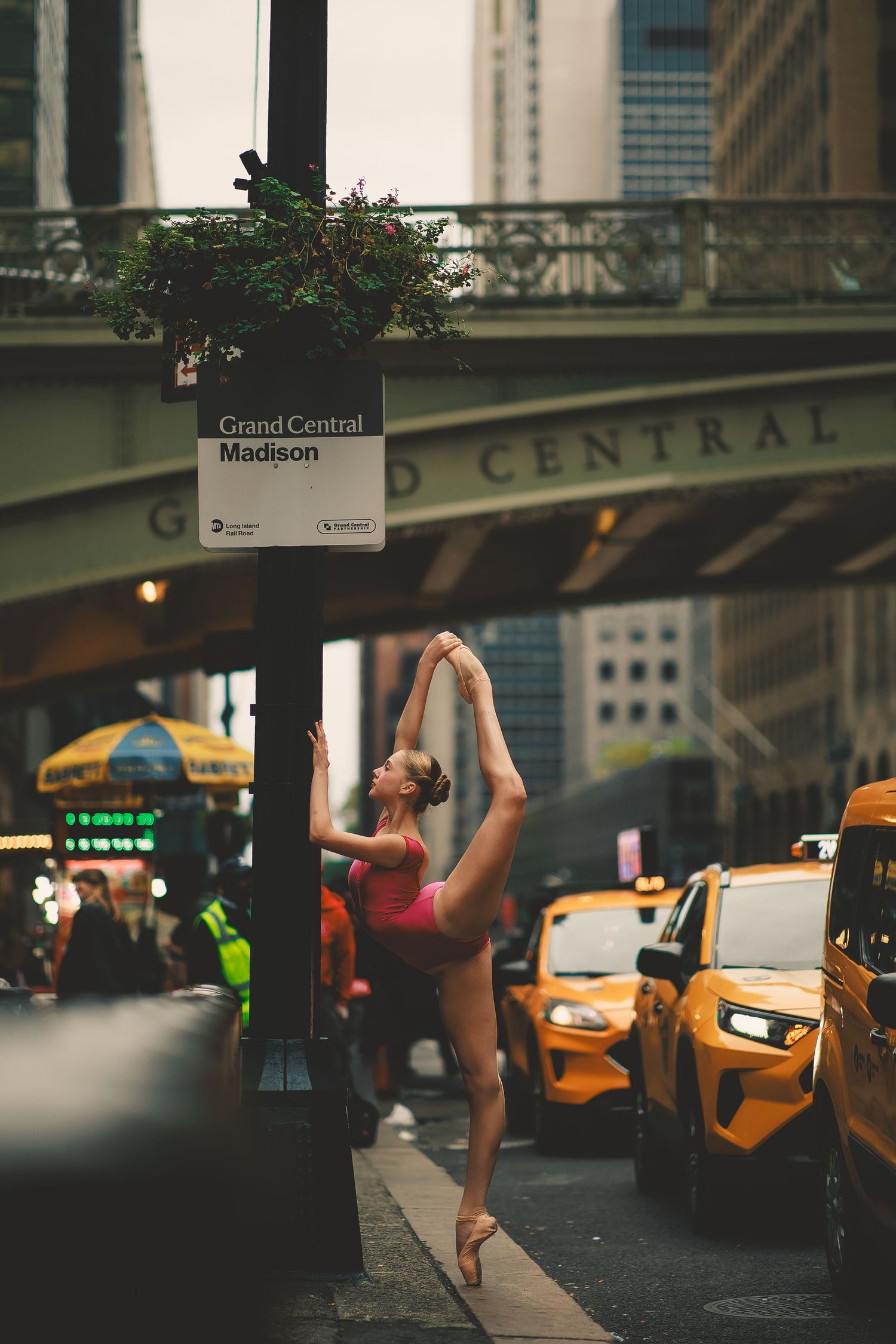 Athletic dancer leaps high in front of basketball hoop on outdoor court.