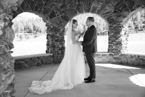 A wedding moment captured through stone archways in black and white photography.