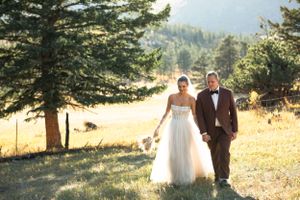 A sunny outdoor wedding photo on a hillside with evergreen trees in the golden afternoon light.