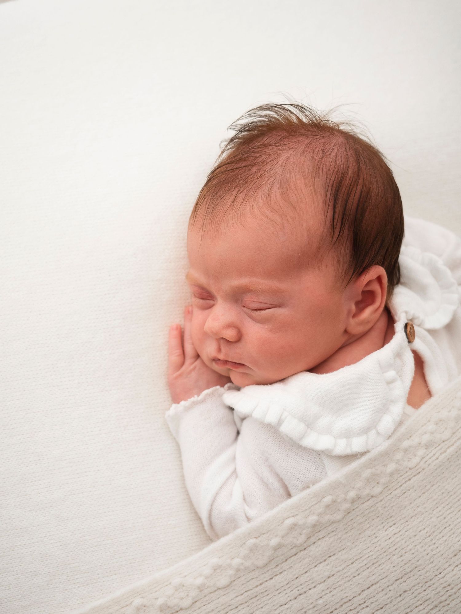 newborn baby girl in white sleeps with hand under cheek, portrait by Verity Photography in Didcot, Oxfordshire