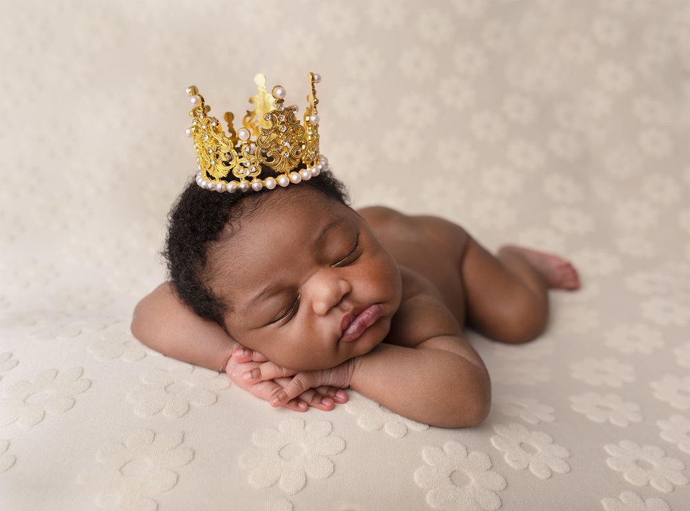 Sleeping newborn baby lies on textured cream blanket during professional photo session.