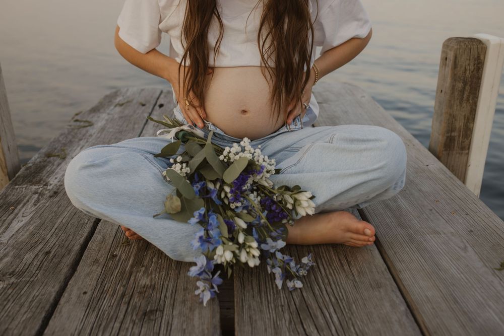 A collection of romantic maternity photos showing a pregnant woman in a white dress holding flowers on a wooden deck.