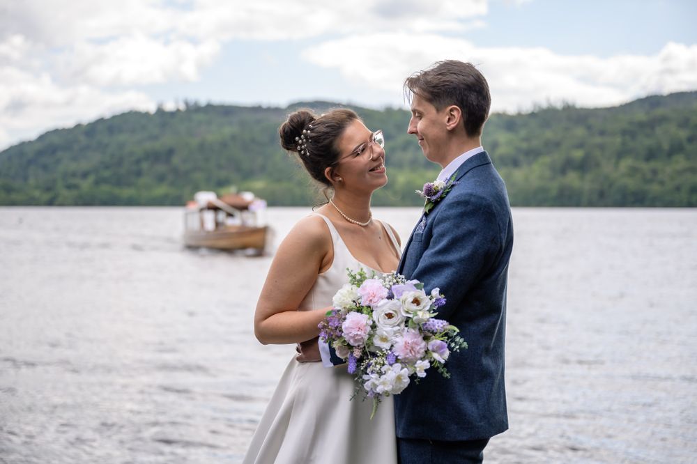 Boat arriving behind bride and groom at Lake District wedding