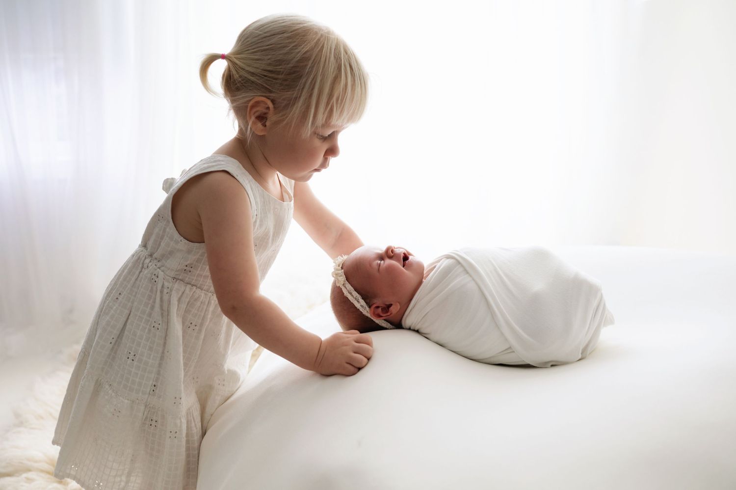 Sibling gently kissing a newborn’s forehead – heartwarming family newborn photography in Woodbury MN