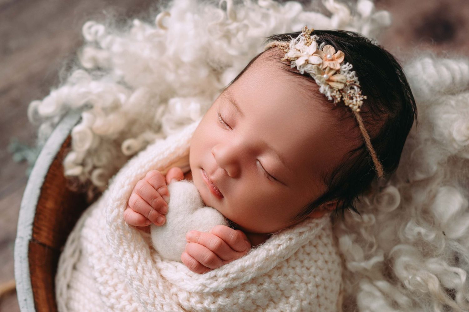 Sleeping newborn swaddled in a delicate, boutique wrap, posed in a cozy basket in studio newborn photography Woodbury MN