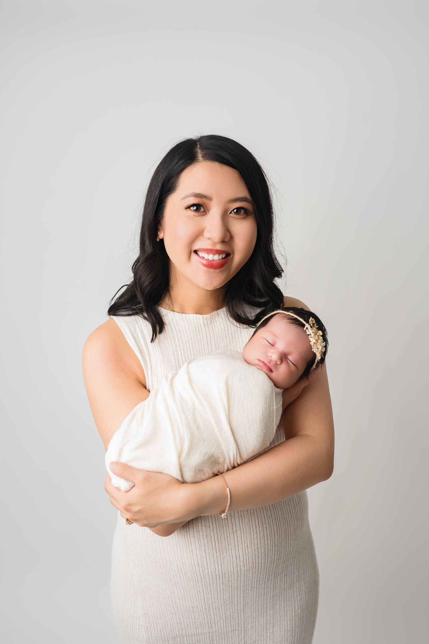 mother holding her baby in her arms and smiling during the newborn session in Woodbury MN