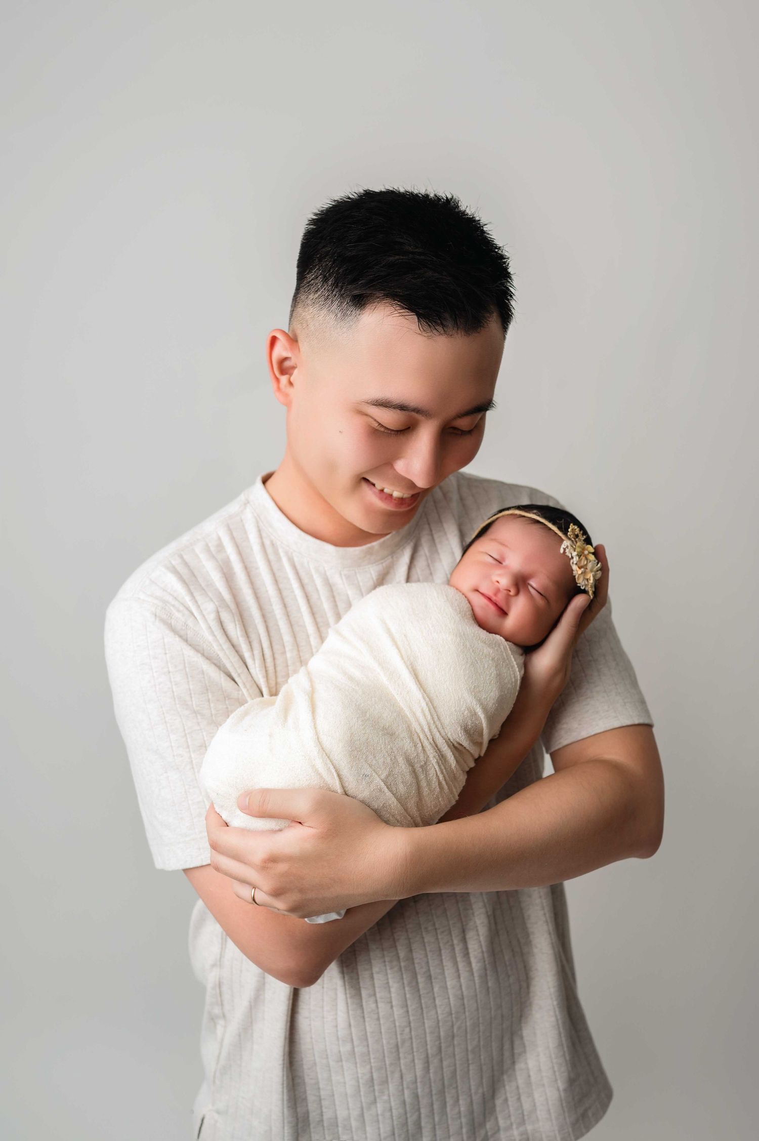 father holding his baby in his arm and smiling during the newborn session in Woodbury MN