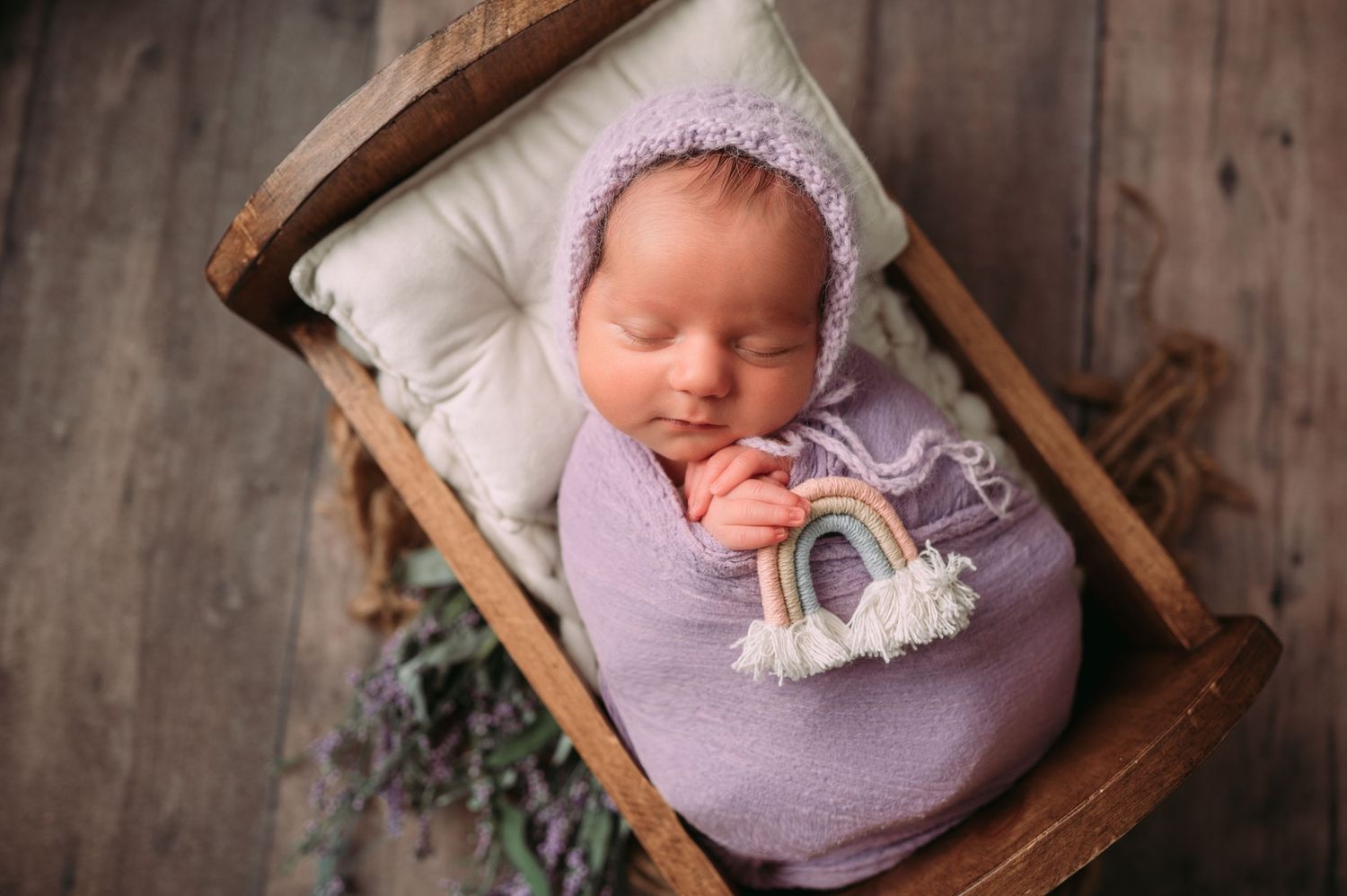 Sleeping newborn swaddled in a delicate, boutique wrap, posed in a cozy bed in studio newborn photography Woodbury MN