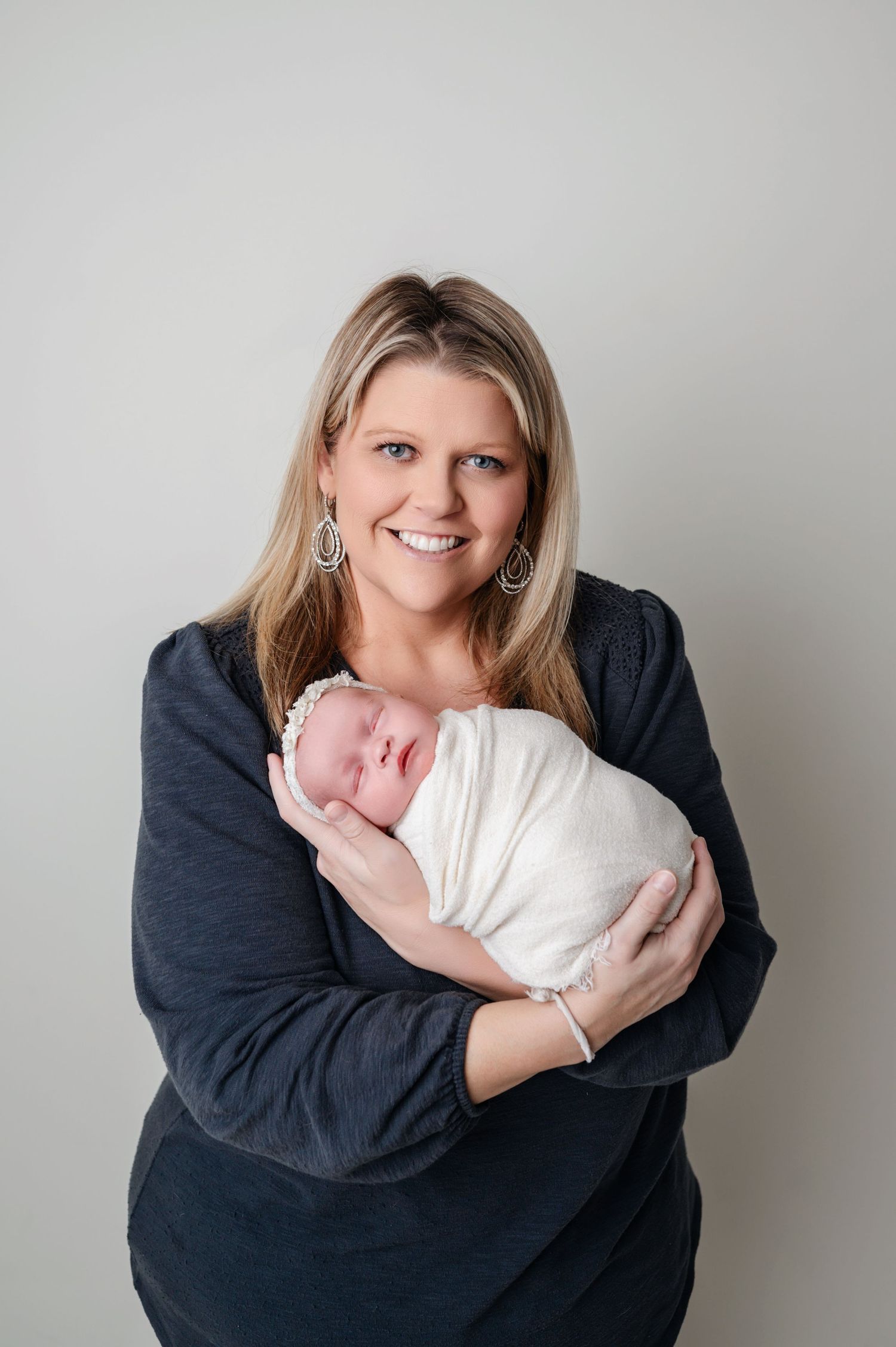 mother holding her baby in her arms and smiling during the newborn session in Woodbury MN