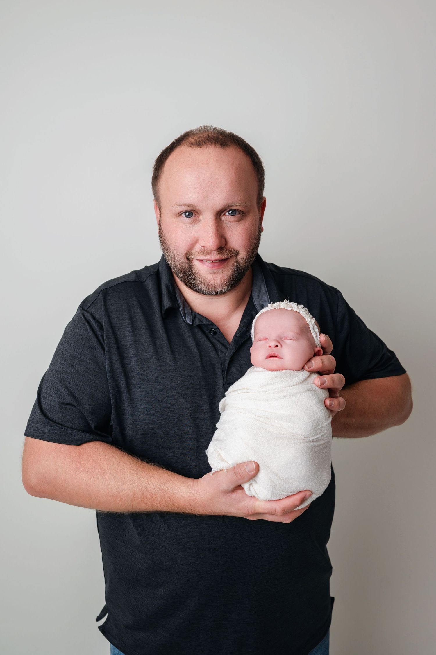 father holding his baby in his arm and smiling during the newborn session in Woodbury MN