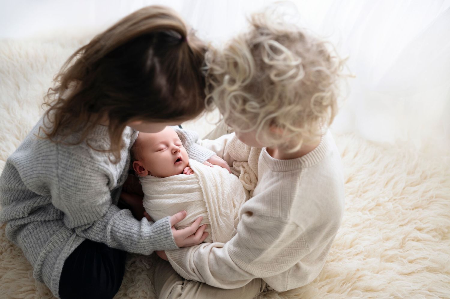 Sibling gently kissing a newborn’s forehead – heartwarming family newborn photography in Woodbury MN