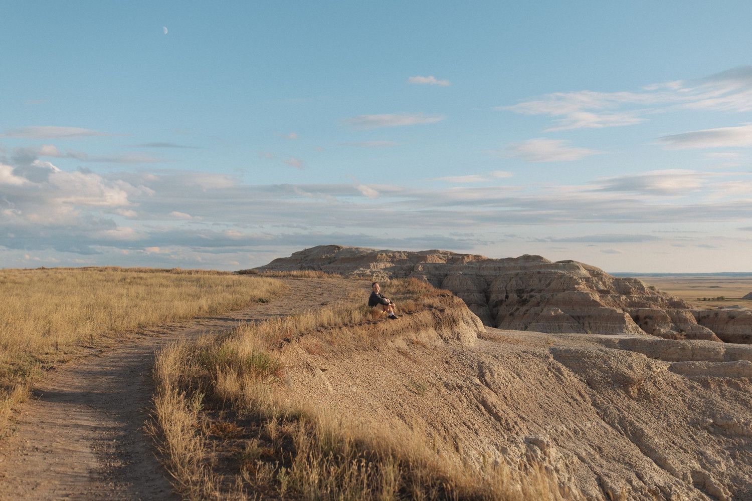 Wide panoramic view of rocky badlands terrain under bright blue sky.