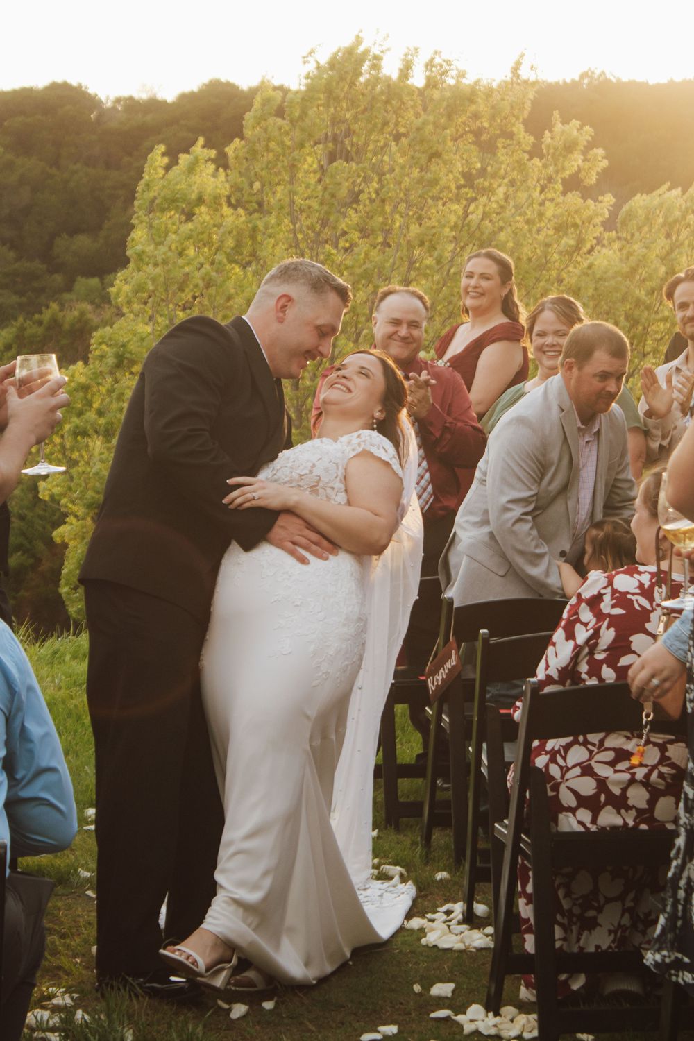Bride and groom share a joyful moment walking down the aisle at an outdoor wedding ceremony at golden hour.