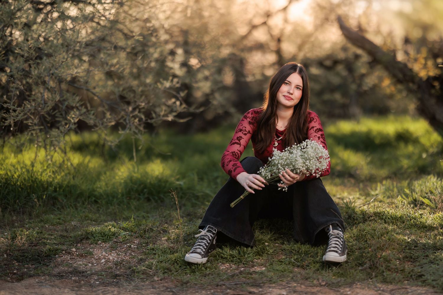 senior girl at catalina state park sitting in the grass holding flowers