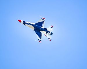 U.S. Air Force Thunderbirds F-16 jet performing aerial maneuver against clear blue sky at airshow.
