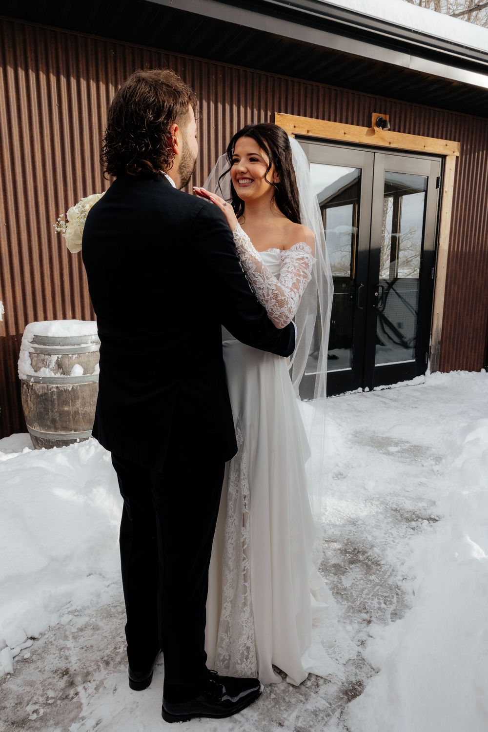Bride and groom share a tender first look moment outdoors in the snow during a winter wedding.